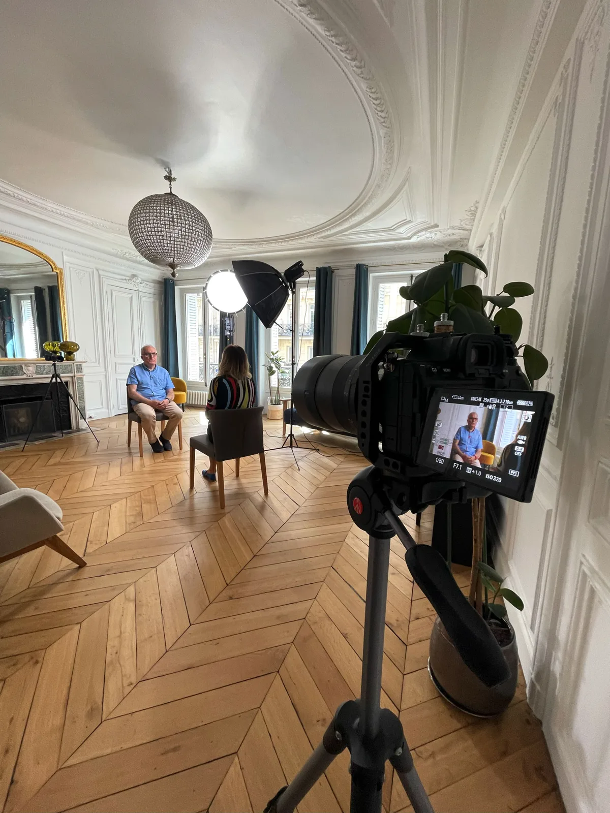 Une caméra et un dispositif d’éclairage installés pour filmer une intervenante dans un lieu de réception